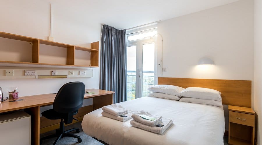 Holland Hall Bedroom at Holland Hall with double bed, desk and window looking outside.