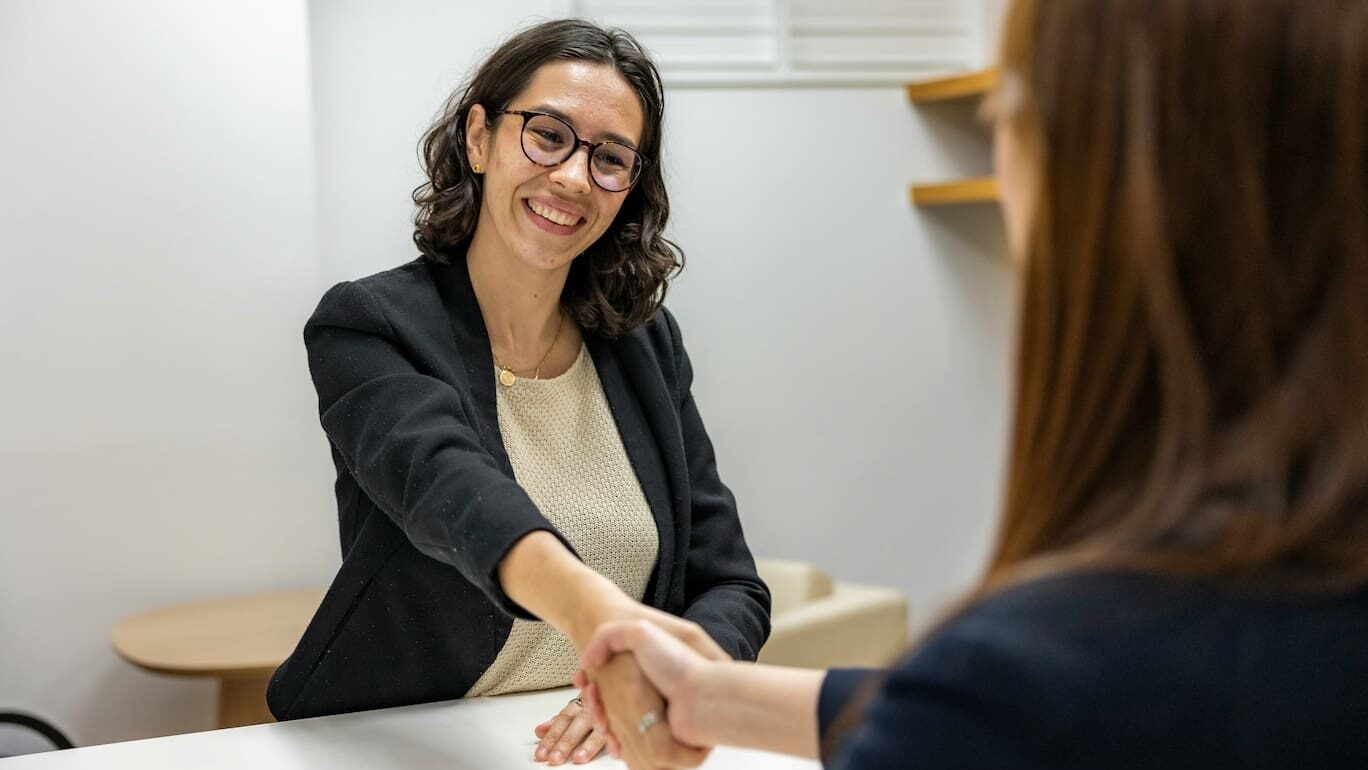 Two women shaking hands and smiling