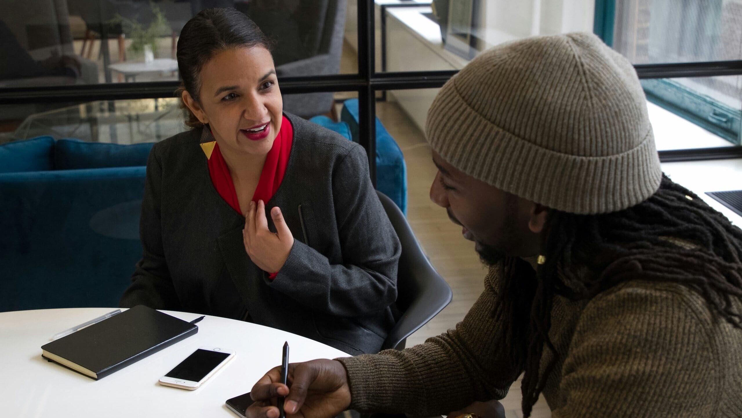 Two people seated around an office table in a meeting.